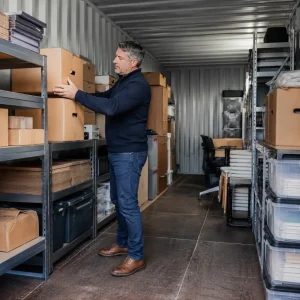 British businessman organising archive boxes inside secure container storage facility efficiently today.